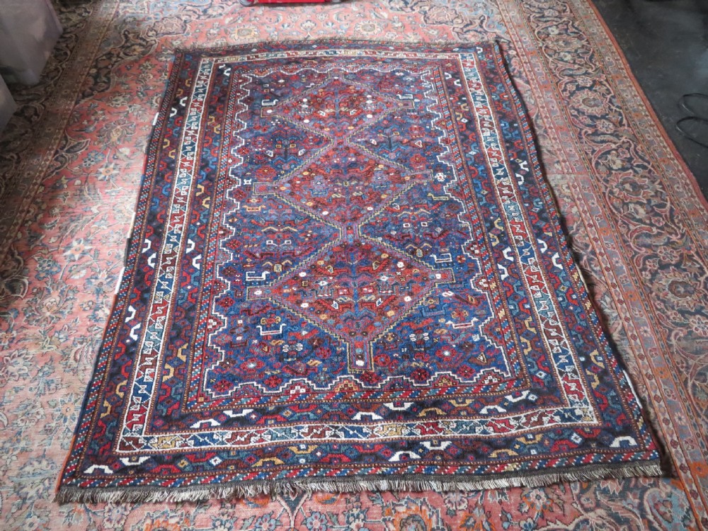 An antique Khamseh hand-knotted wool tribal rug featuring three central diamond medallions surrounded by small bird and geometric motifs in deep blue, terracotta red, and cream. View XXIV