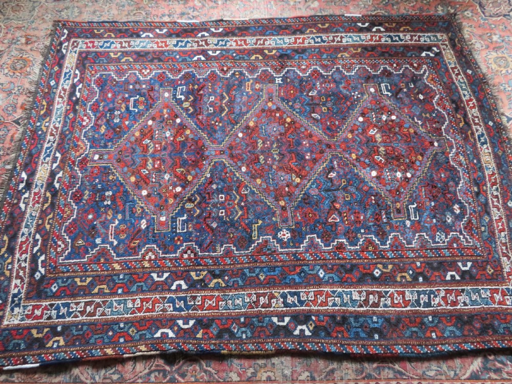 An antique Khamseh hand-knotted wool tribal rug featuring three central diamond medallions surrounded by small bird and geometric motifs in deep blue, terracotta red, and cream. View XXV
