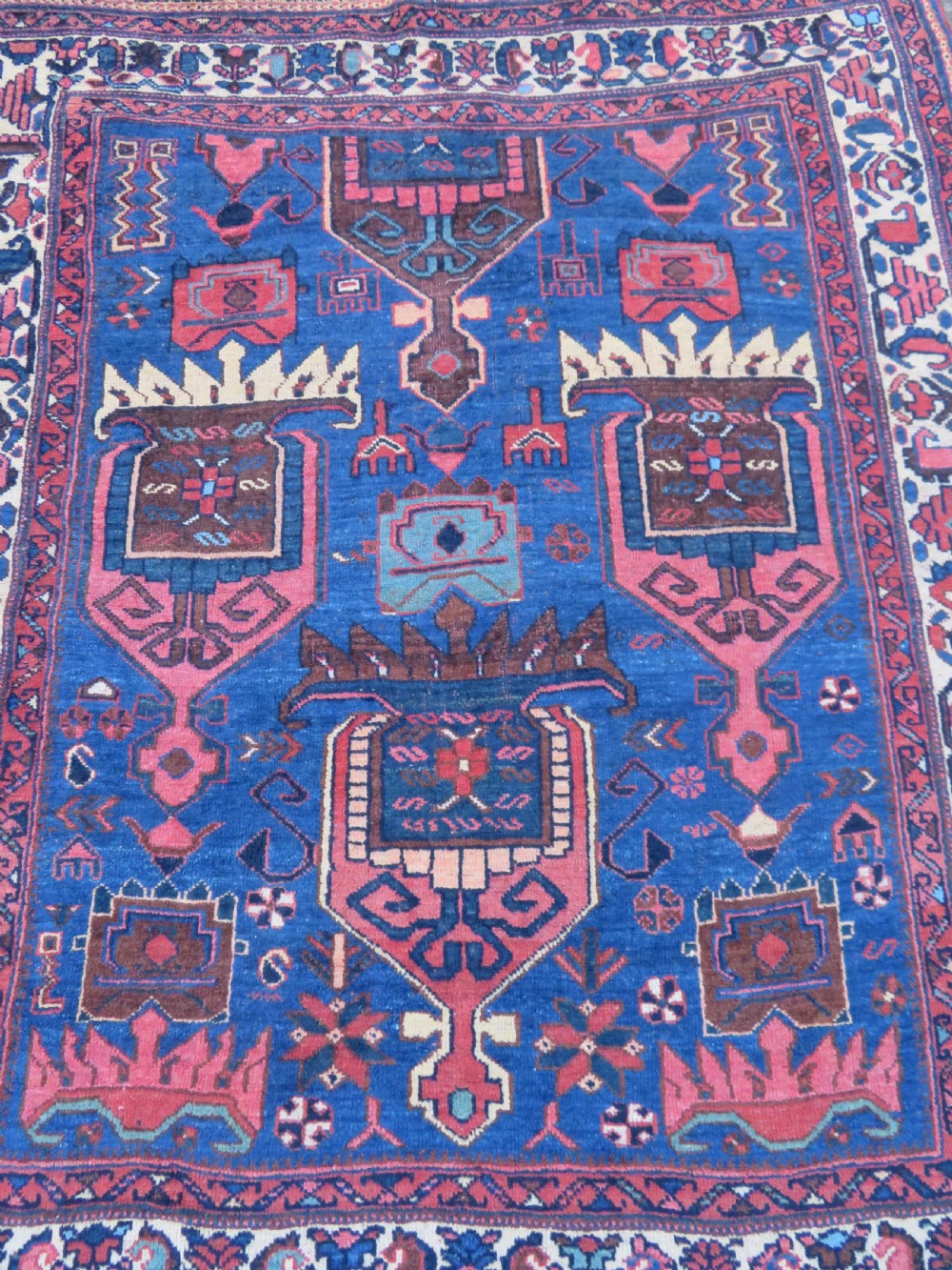 An antique hand-knotted Afshar wool rug featuring a vibrant indigo blue central field with stylized geometric medallions surrounded by detailed terracotta red and ivory borders. View III