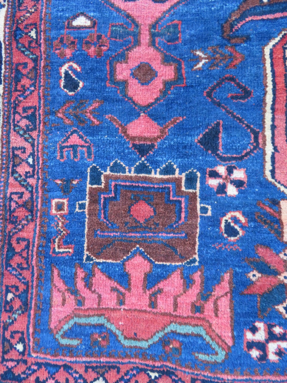An antique hand-knotted Afshar wool rug featuring a vibrant indigo blue central field with stylized geometric medallions surrounded by detailed terracotta red and ivory borders. View IV