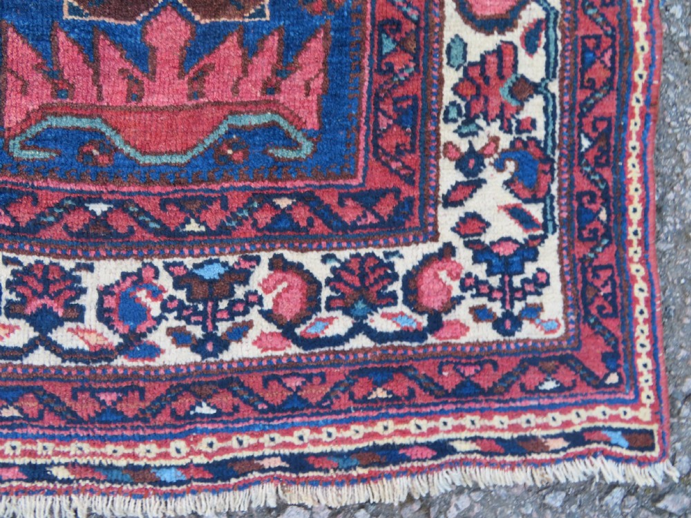 An antique hand-knotted Afshar wool rug featuring a vibrant indigo blue central field with stylized geometric medallions surrounded by detailed terracotta red and ivory borders. View VI
