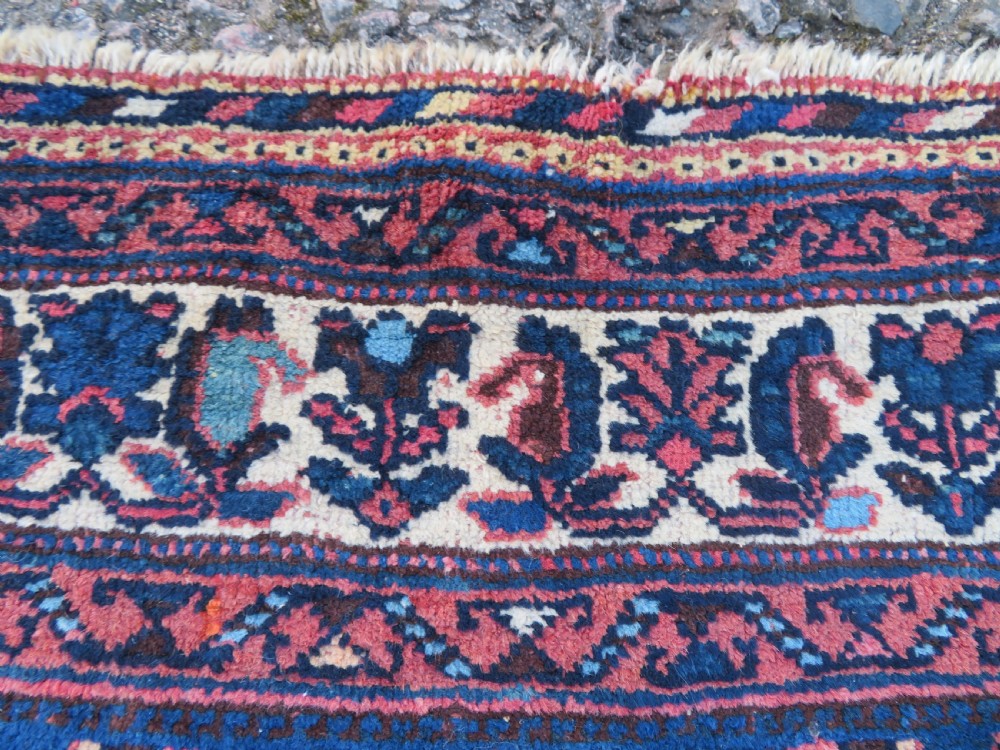 An antique hand-knotted Afshar wool rug featuring a vibrant indigo blue central field with stylized geometric medallions surrounded by detailed terracotta red and ivory borders. View IX