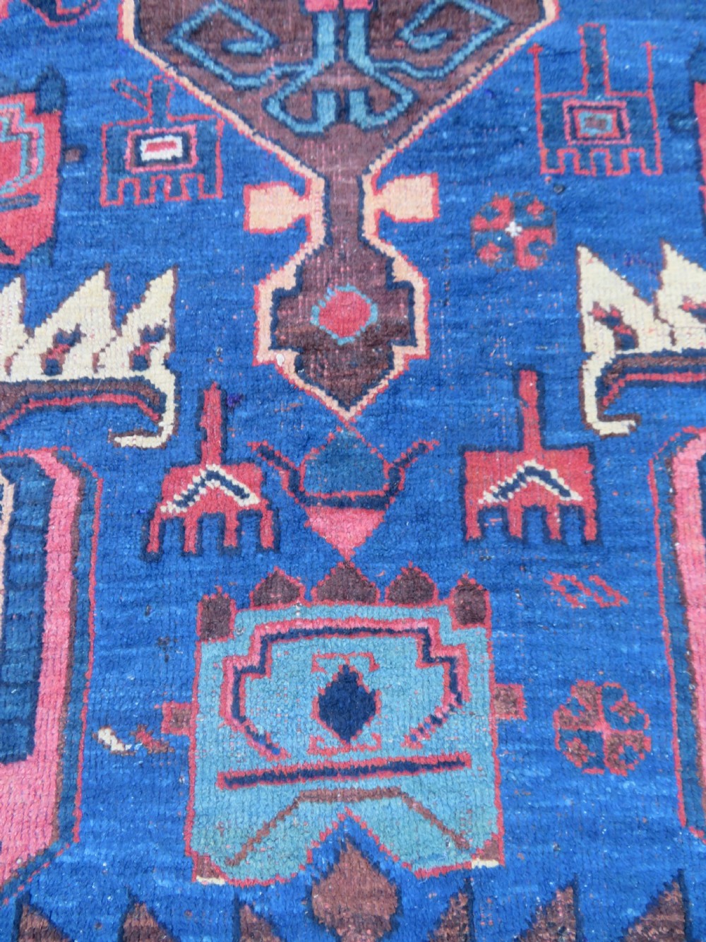 An antique hand-knotted Afshar wool rug featuring a vibrant indigo blue central field with stylized geometric medallions surrounded by detailed terracotta red and ivory borders. View X