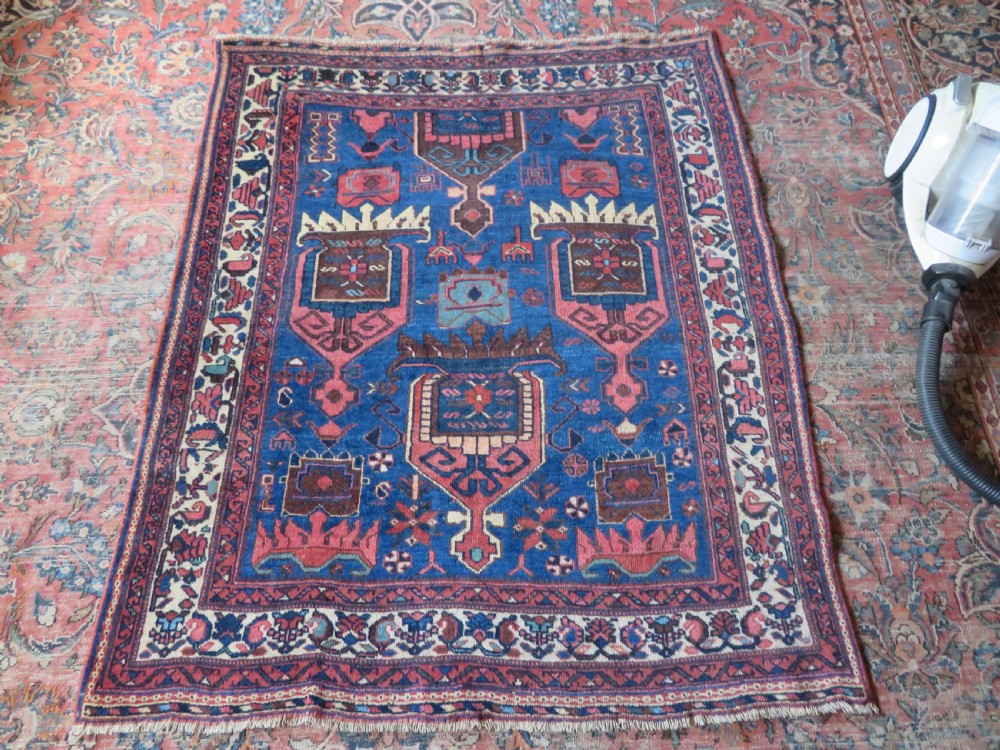 An antique hand-knotted Afshar wool rug featuring a vibrant indigo blue central field with stylized geometric medallions surrounded by detailed terracotta red and ivory borders. View XXII