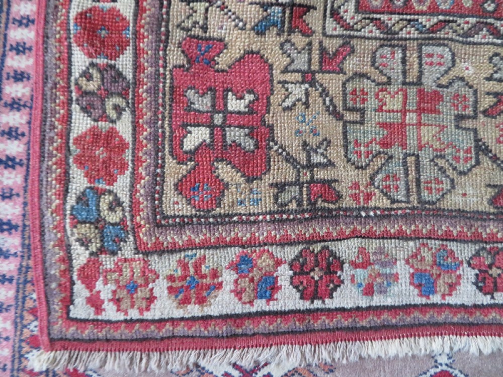 An antique hand-knotted Turkish Milas wool prayer rug featuring a central pointed arch motif in terracotta surrounded by broad geometric floral borders in cream, red, and blue shades. View IV