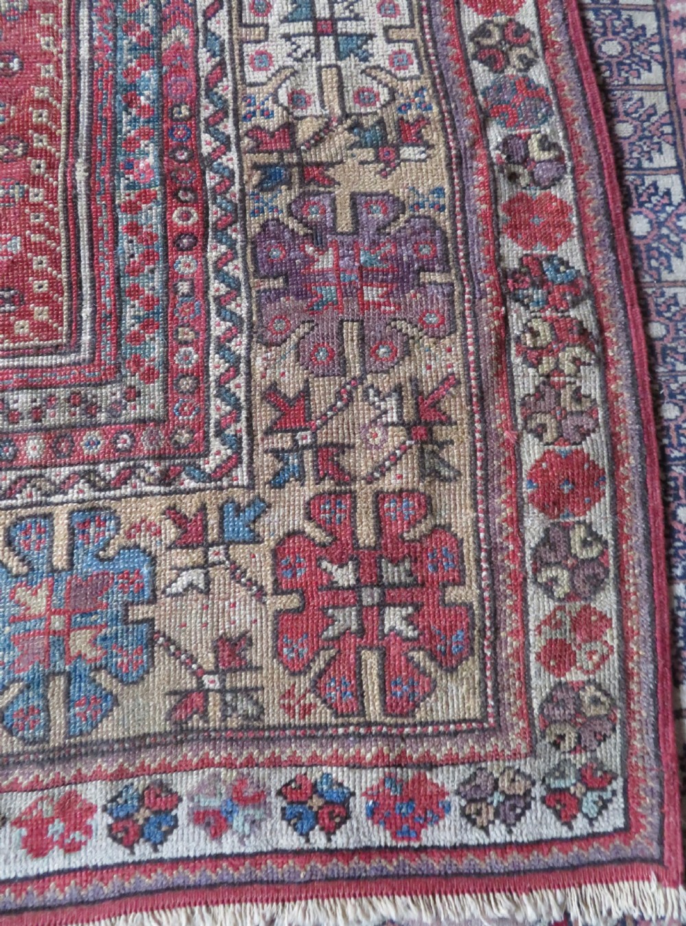 An antique hand-knotted Turkish Milas wool prayer rug featuring a central pointed arch motif in terracotta surrounded by broad geometric floral borders in cream, red, and blue shades. View V
