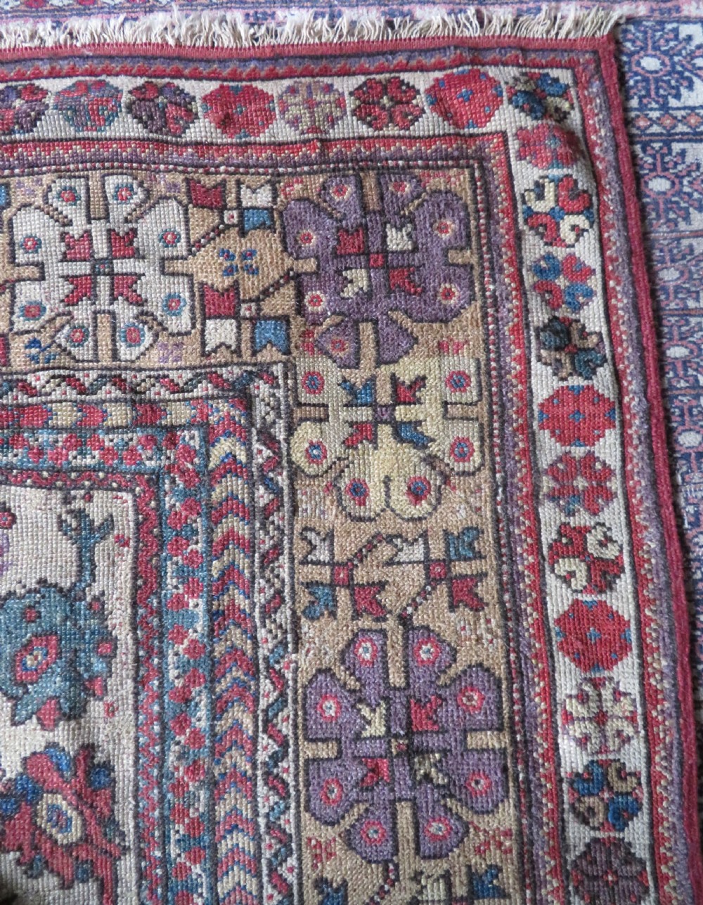 An antique hand-knotted Turkish Milas wool prayer rug featuring a central pointed arch motif in terracotta surrounded by broad geometric floral borders in cream, red, and blue shades. View VII