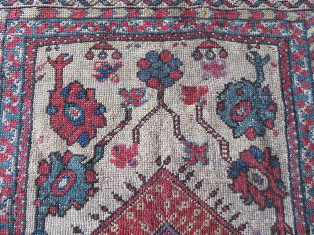 An antique hand-knotted Turkish Milas wool prayer rug featuring a central pointed arch motif in terracotta surrounded by broad geometric floral borders in cream, red, and blue shades. View VIII