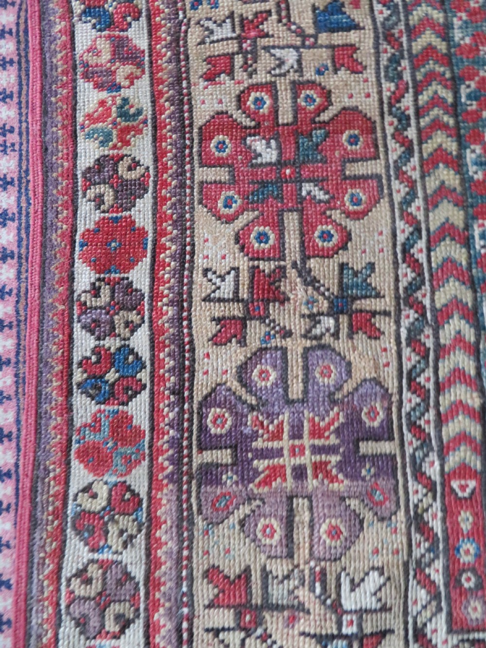 An antique hand-knotted Turkish Milas wool prayer rug featuring a central pointed arch motif in terracotta surrounded by broad geometric floral borders in cream, red, and blue shades. View X