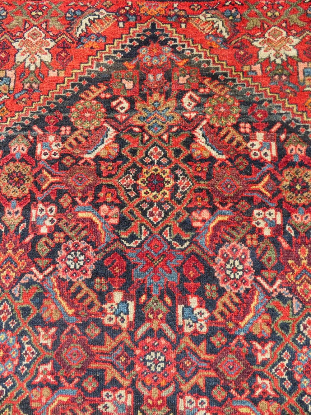 A hand-knotted antique Malayer rug featuring a central navy diamond medallion surrounded by elaborate geometric red and floral pattern borders. View IV