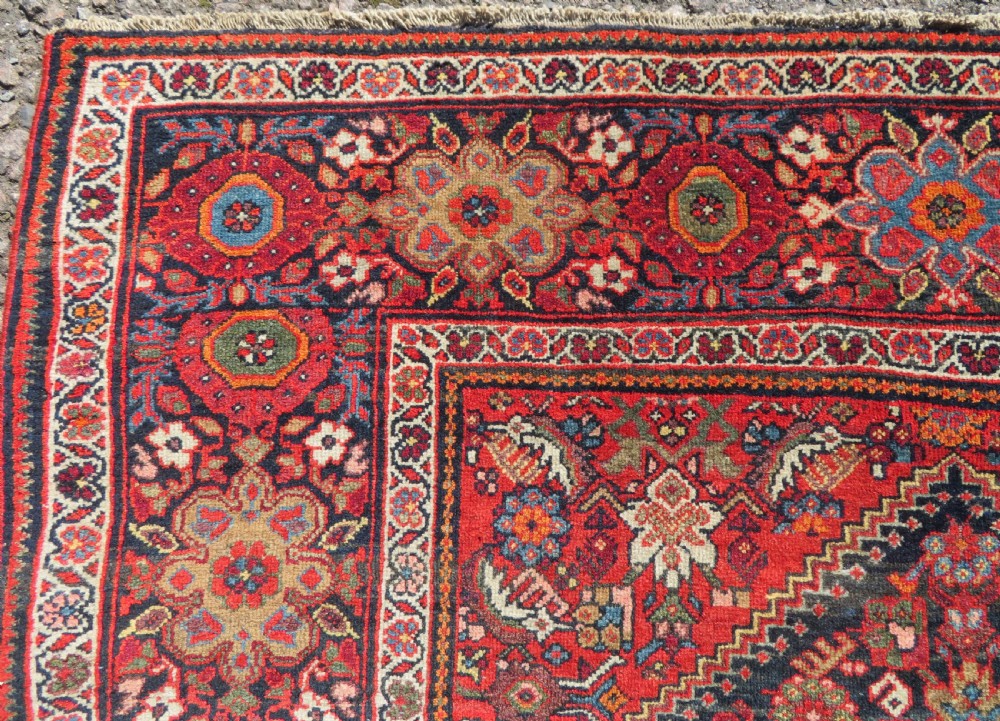 A hand-knotted antique Malayer rug featuring a central navy diamond medallion surrounded by elaborate geometric red and floral pattern borders. View V