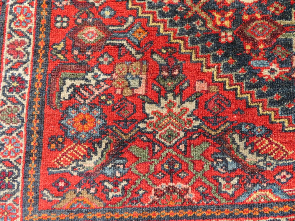 A hand-knotted antique Malayer rug featuring a central navy diamond medallion surrounded by elaborate geometric red and floral pattern borders. View XI