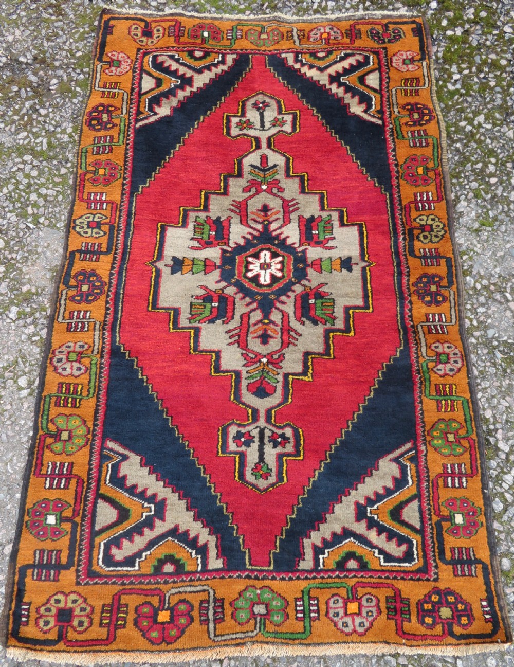 A hand-knotted Turkish Yahyali rug featuring a stepped central medallion in red, navy blue, and beige, framed by a broad ochre geometric border.