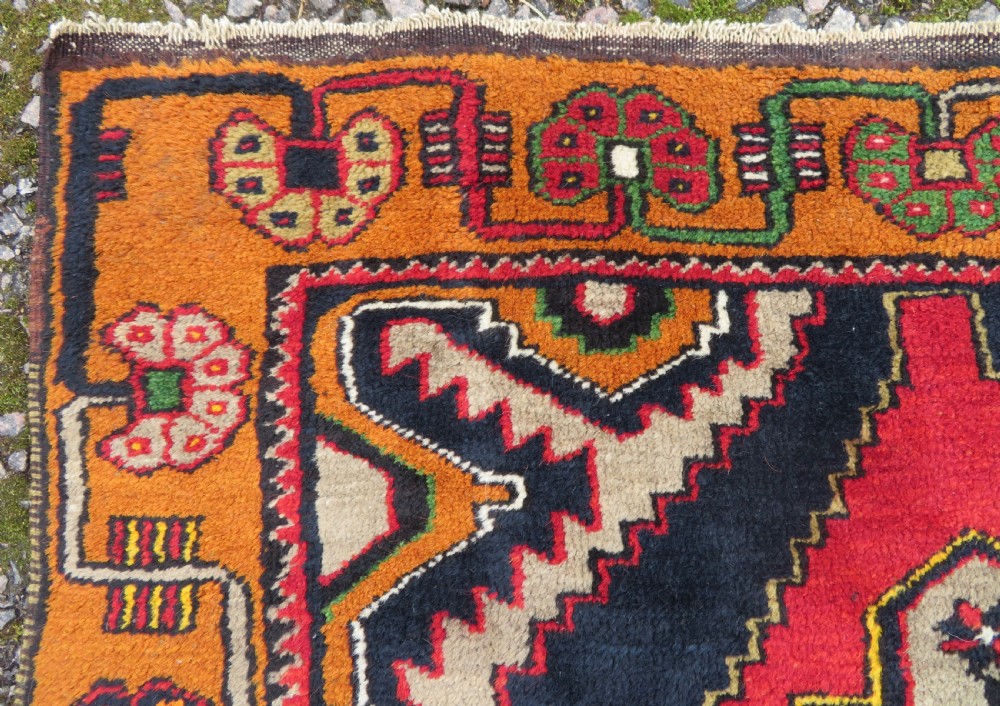 A hand-knotted Turkish Yahyali rug featuring a stepped central medallion in red, navy blue, and beige, framed by a broad ochre geometric border. View VI