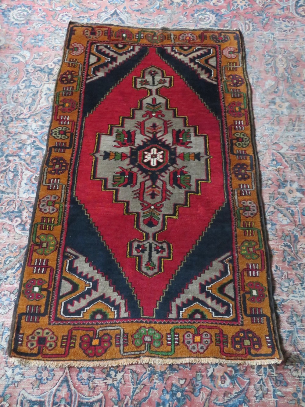 A hand-knotted Turkish Yahyali rug featuring a stepped central medallion in red, navy blue, and beige, framed by a broad ochre geometric border. View XIII