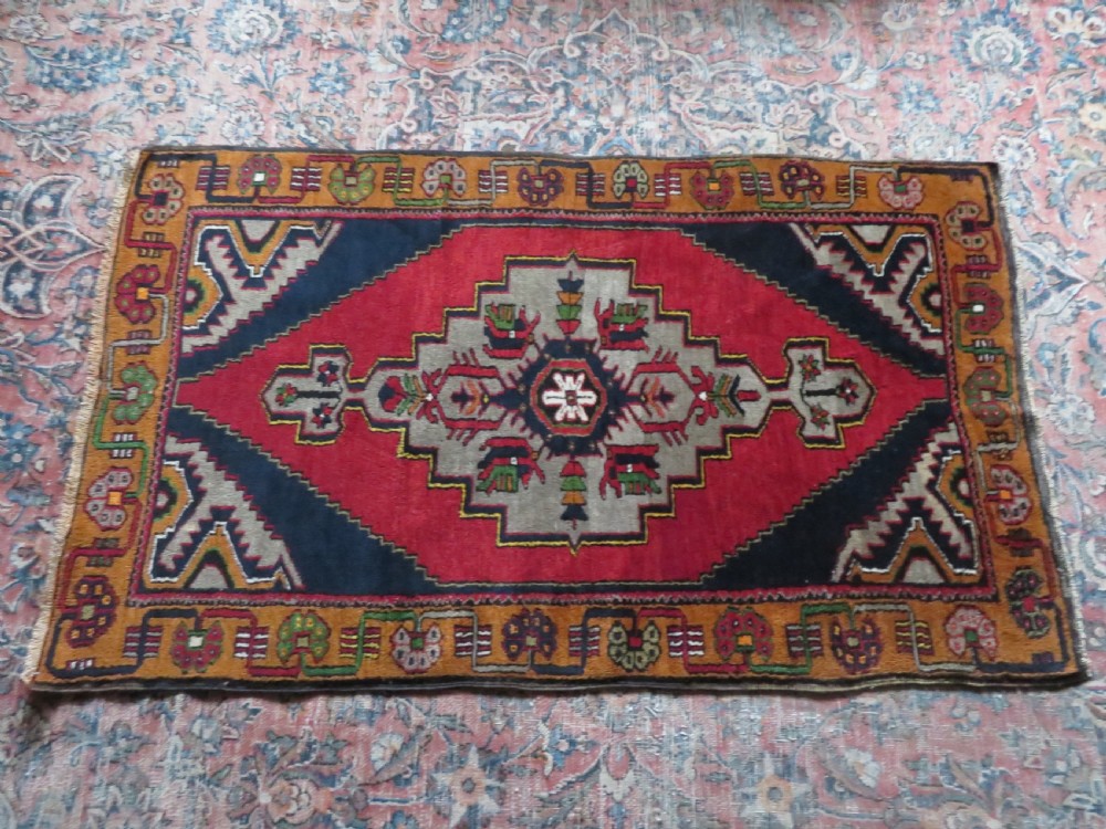 A hand-knotted Turkish Yahyali rug featuring a stepped central medallion in red, navy blue, and beige, framed by a broad ochre geometric border. View XIV