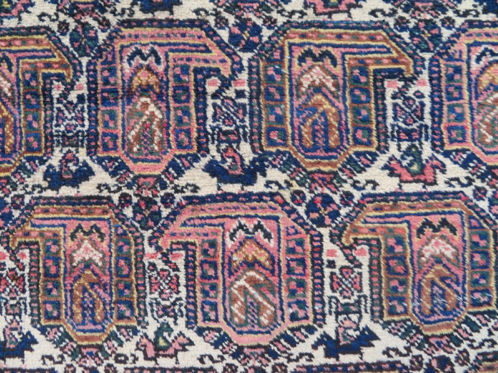 An antique hand-knotted Afshar wool rug featuring a repeating geometric motif on an ivory ground with dark blue and terracotta decorative borders. View II