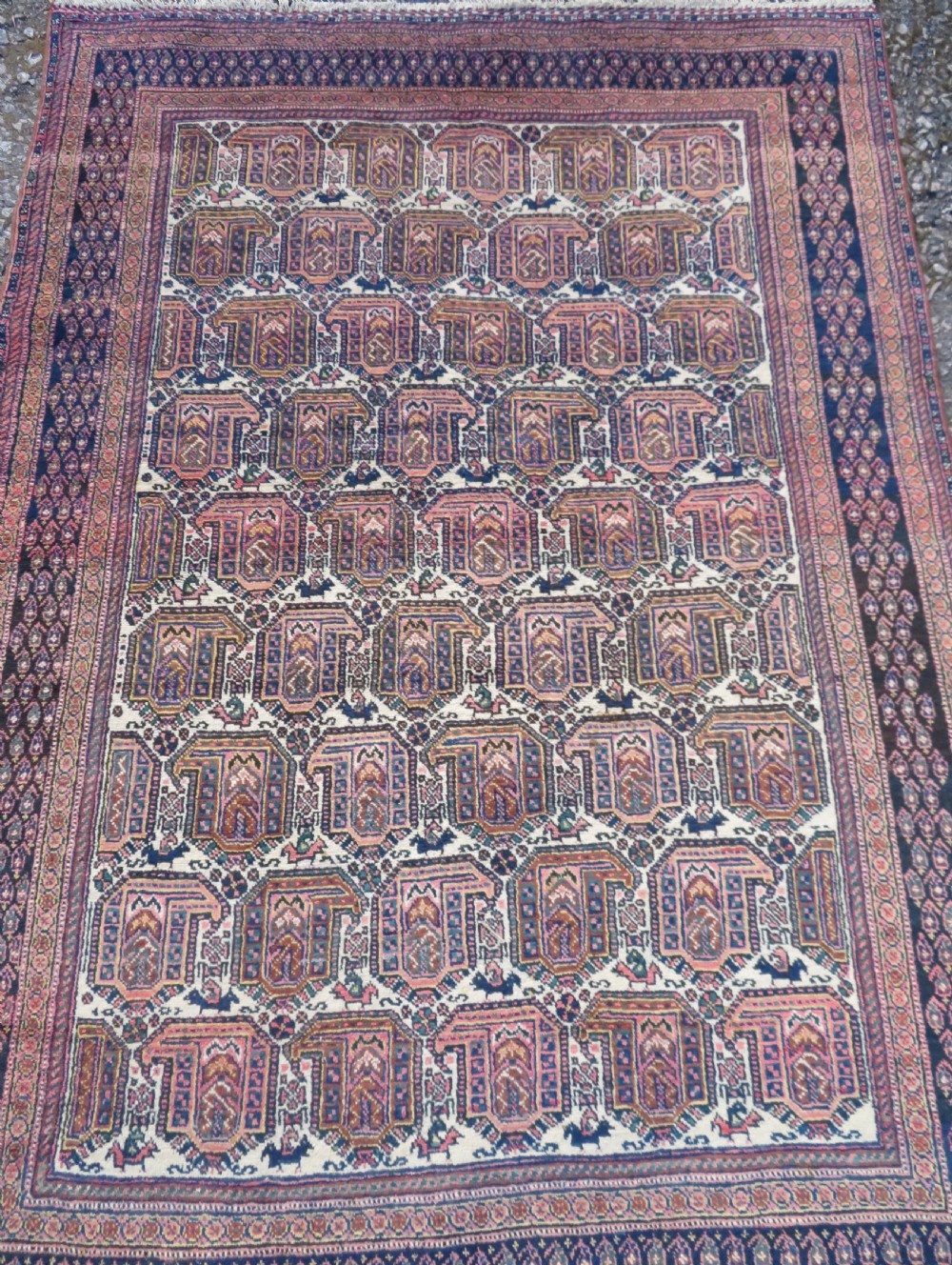 An antique hand-knotted Afshar wool rug featuring a repeating geometric motif on an ivory ground with dark blue and terracotta decorative borders. View III