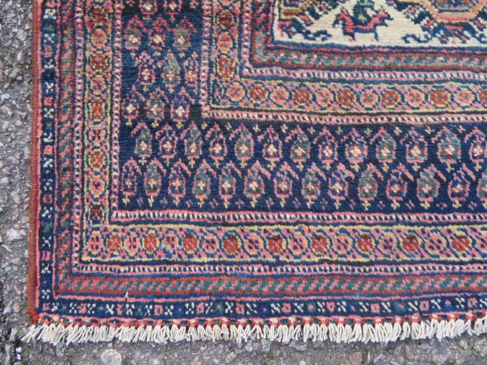 An antique hand-knotted Afshar wool rug featuring a repeating geometric motif on an ivory ground with dark blue and terracotta decorative borders. View V