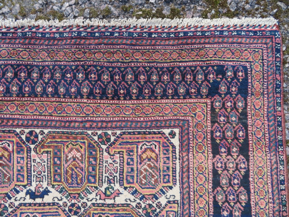 An antique hand-knotted Afshar wool rug featuring a repeating geometric motif on an ivory ground with dark blue and terracotta decorative borders. View VIII