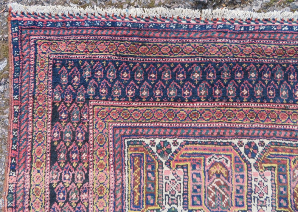 An antique hand-knotted Afshar wool rug featuring a repeating geometric motif on an ivory ground with dark blue and terracotta decorative borders. View IX