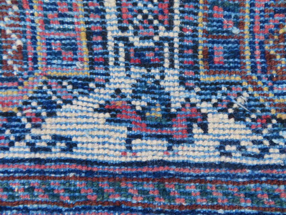 An antique hand-knotted Afshar wool rug featuring a repeating geometric motif on an ivory ground with dark blue and terracotta decorative borders. View XVII