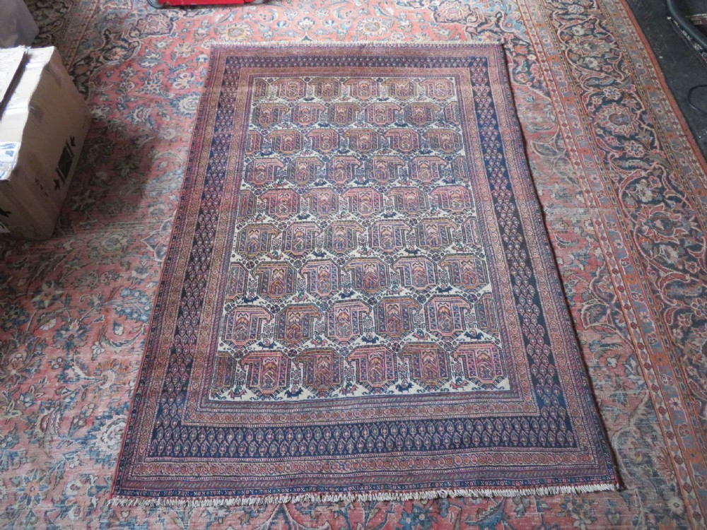 An antique hand-knotted Afshar wool rug featuring a repeating geometric motif on an ivory ground with dark blue and terracotta decorative borders. View XVIII