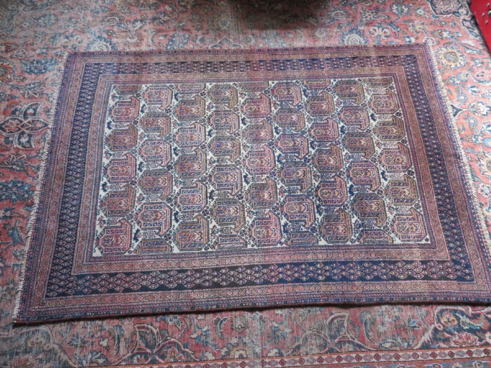 An antique hand-knotted Afshar wool rug featuring a repeating geometric motif on an ivory ground with dark blue and terracotta decorative borders. View XIX