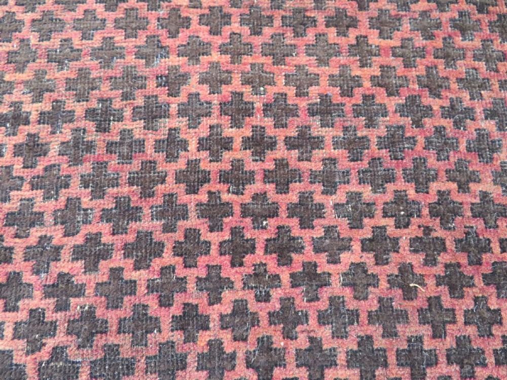 An antique Baluch prayer rug featuring a dark red and brown geometric grid pattern inside a defined mihrab arch with woven fringed ends. View VIII
