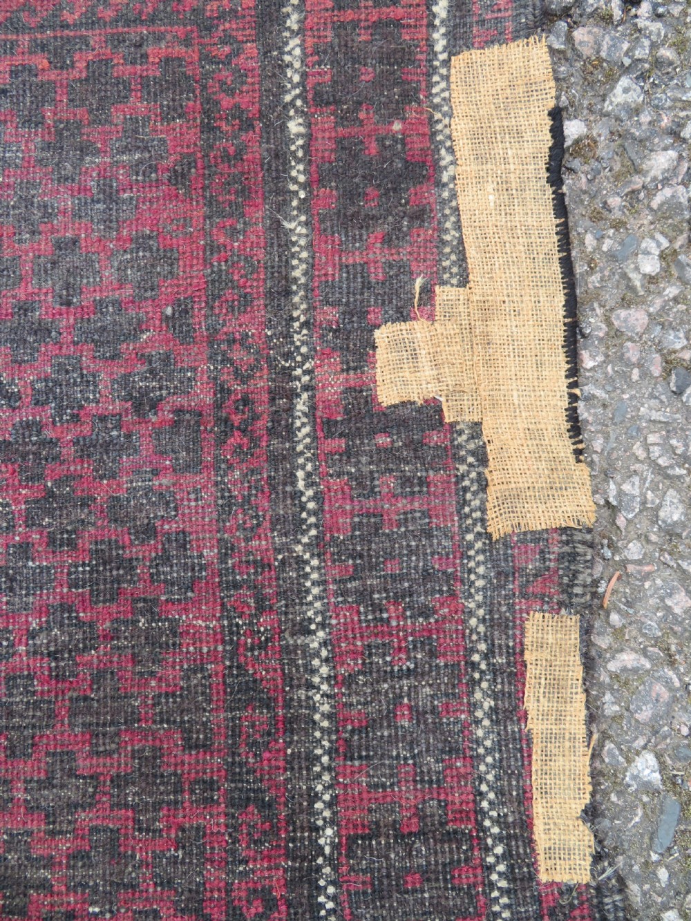 An antique Baluch prayer rug featuring a dark red and brown geometric grid pattern inside a defined mihrab arch with woven fringed ends. View XII