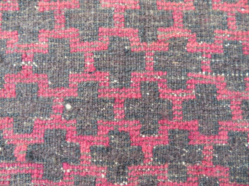 An antique Baluch prayer rug featuring a dark red and brown geometric grid pattern inside a defined mihrab arch with woven fringed ends. View XV