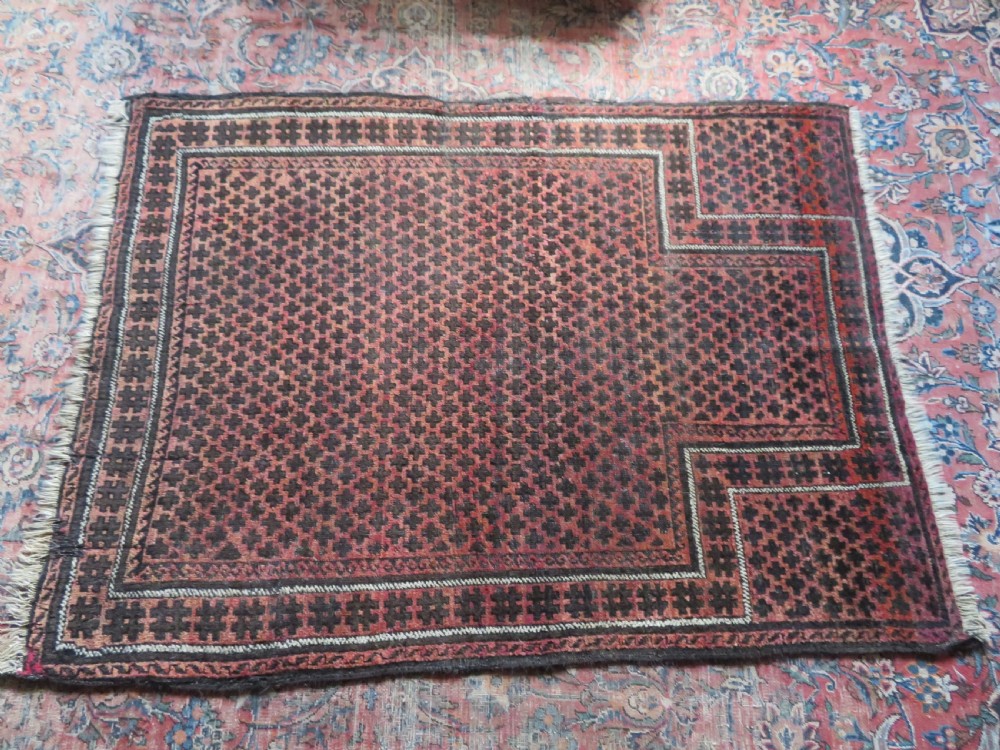 An antique Baluch prayer rug featuring a dark red and brown geometric grid pattern inside a defined mihrab arch with woven fringed ends. View XX