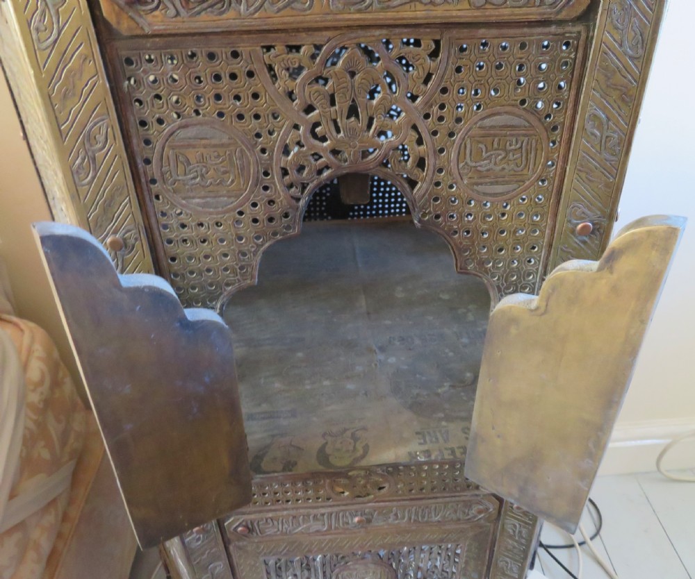 A tall hexagonal brass occasional table featuring intricate openwork latticework, Arabic calligraphic bands, copper and white-metal inlays, arched side openings, and turned feet. View IV