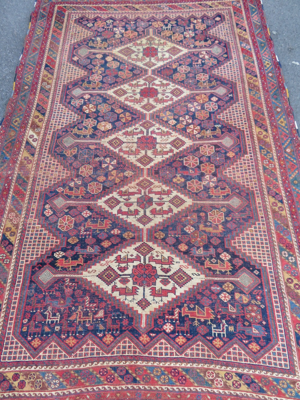 An antique Khamseh hand-knotted wool rug featuring five central diamond medallions on a dark navy and red field decorated with tribal bird motifs. View II