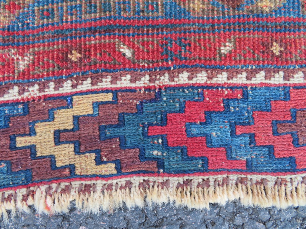 An antique Khamseh hand-knotted wool rug featuring five central diamond medallions on a dark navy and red field decorated with tribal bird motifs. View V