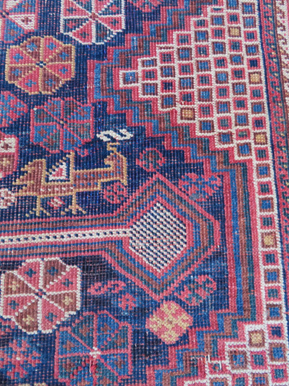 An antique Khamseh hand-knotted wool rug featuring five central diamond medallions on a dark navy and red field decorated with tribal bird motifs. View IX