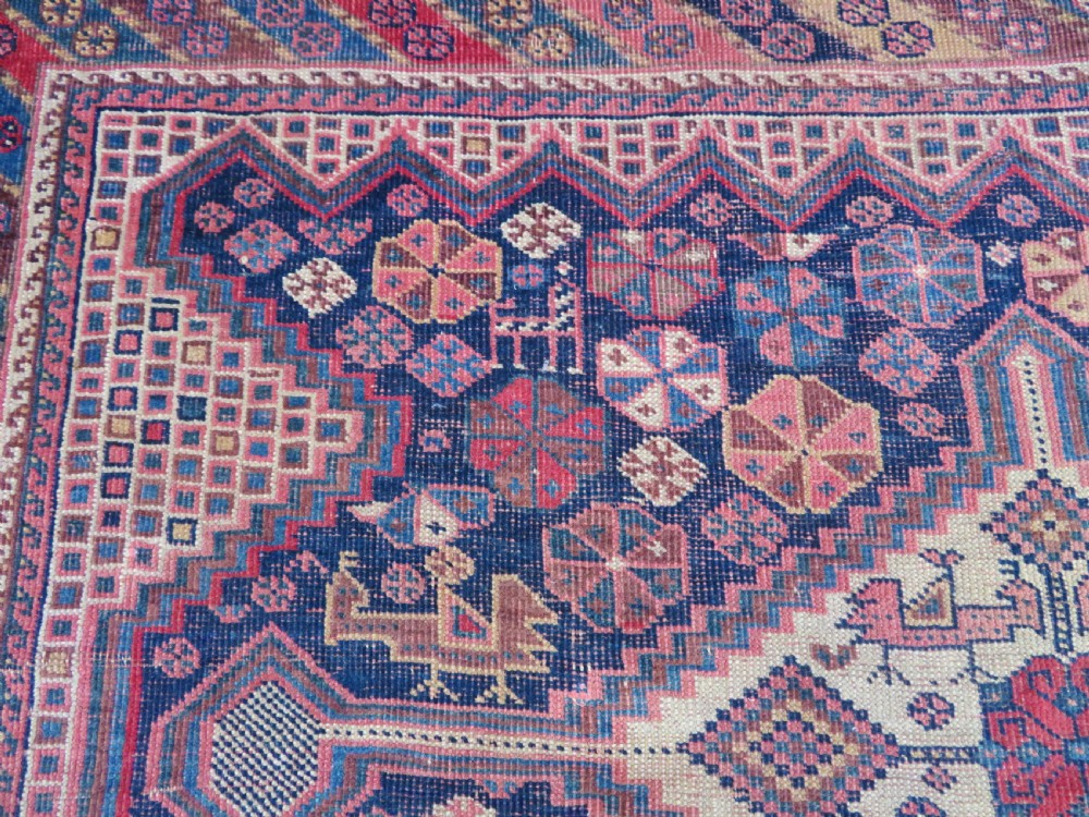 An antique Khamseh hand-knotted wool rug featuring five central diamond medallions on a dark navy and red field decorated with tribal bird motifs. View XIII