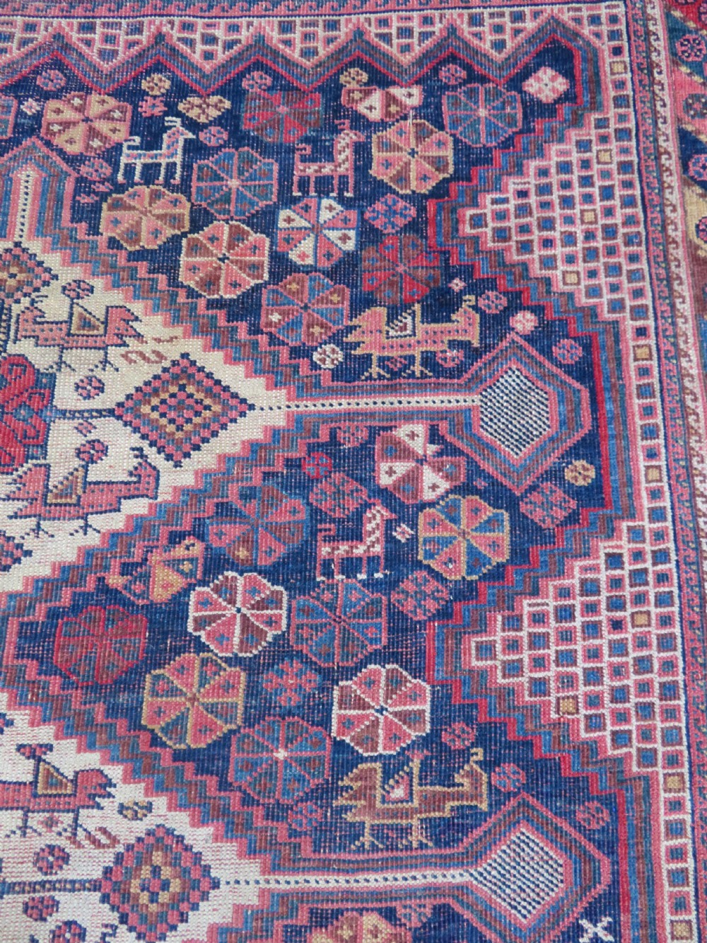 An antique Khamseh hand-knotted wool rug featuring five central diamond medallions on a dark navy and red field decorated with tribal bird motifs. View XIX