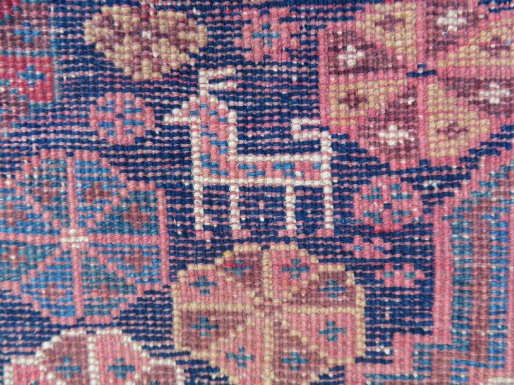 An antique Khamseh hand-knotted wool rug featuring five central diamond medallions on a dark navy and red field decorated with tribal bird motifs. View XXIV