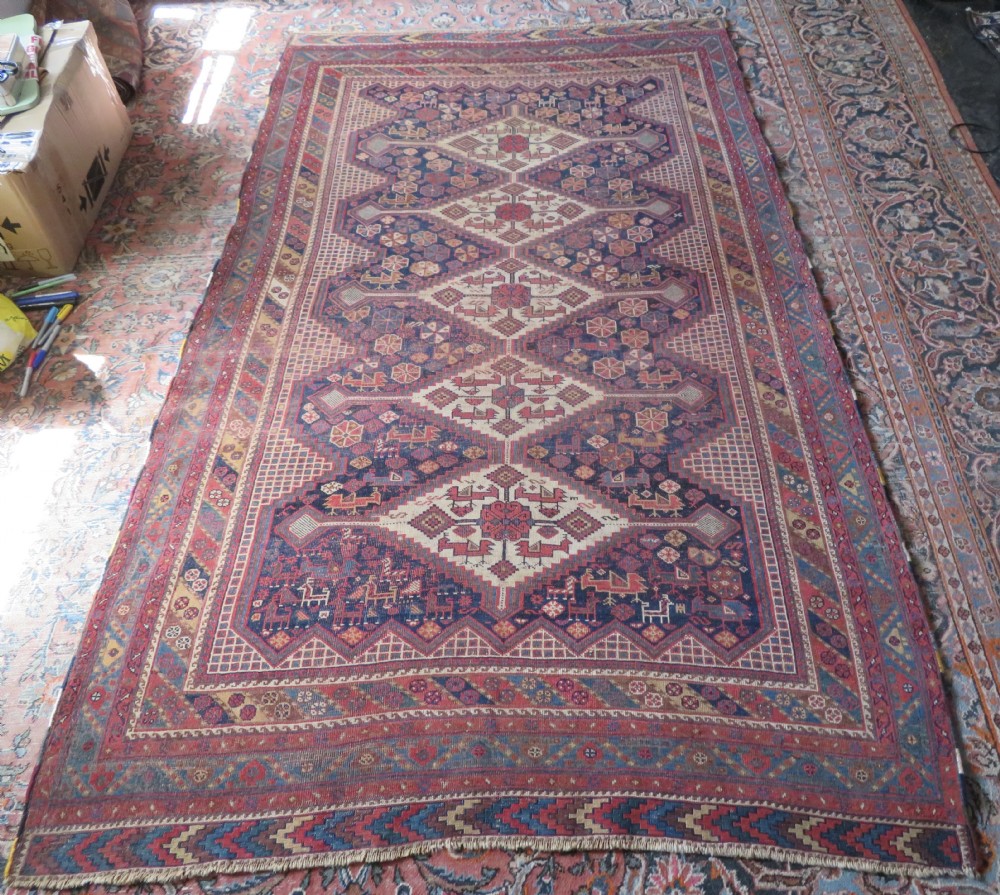 An antique Khamseh hand-knotted wool rug featuring five central diamond medallions on a dark navy and red field decorated with tribal bird motifs. View XXV