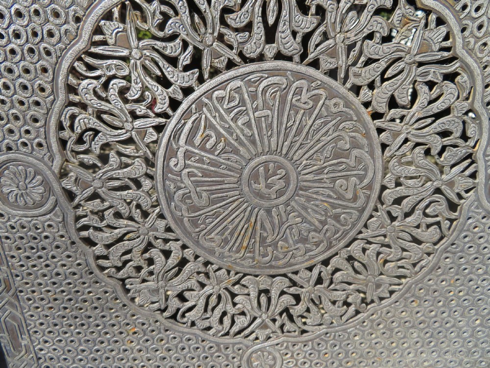 An octagonal brass and copper Cairoware Quran stand featuring Arabic calligraphy, pierced fretwork panels, silver inlay, and top dome finials crowned with crescent moons. View XII