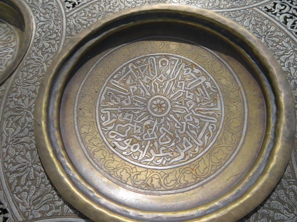An octagonal brass and copper Cairoware Quran stand featuring Arabic calligraphy, pierced fretwork panels, silver inlay, and top dome finials crowned with crescent moons. View XVIII
