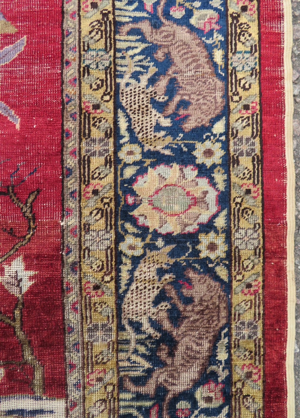 A 19th-century West Anatolian silk rug featuring a red central panel depicting horseback hunters, surrounded by a floral and animal motif navy border. View VIII