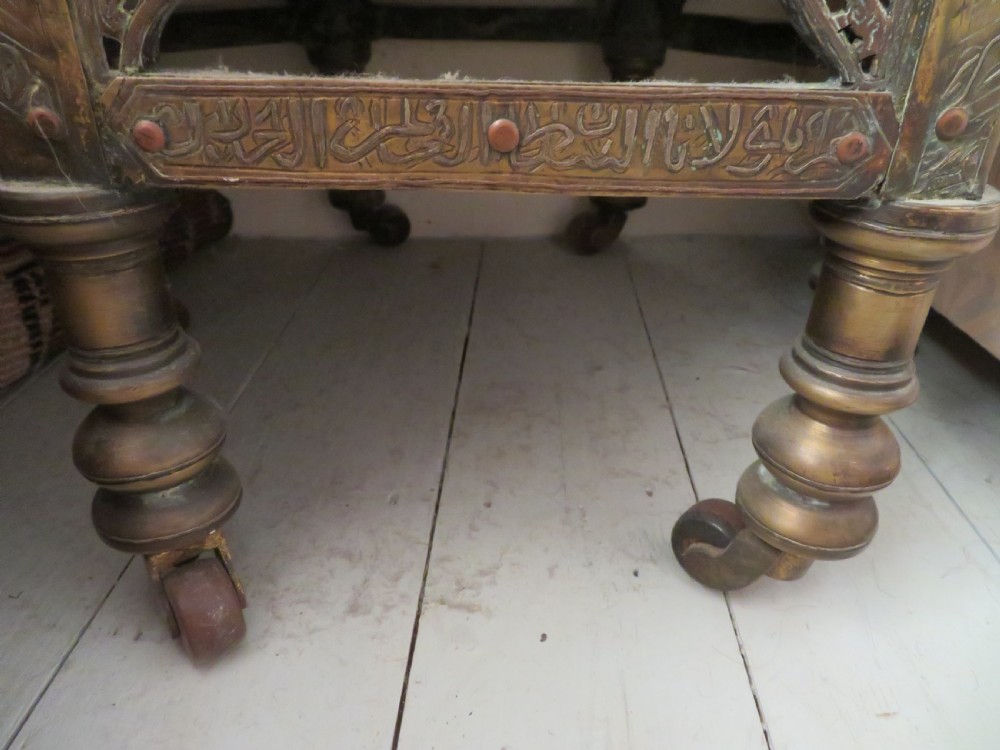 A hexagonal antique brass occasional table with pierced openwork panels, Arabic calligraphic inlays in copper and white metal, and double cabinet doors. View VI