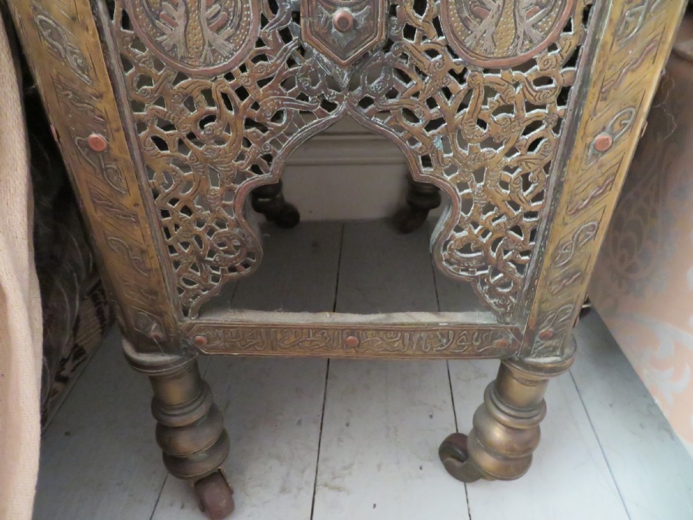 A hexagonal antique brass occasional table with pierced openwork panels, Arabic calligraphic inlays in copper and white metal, and double cabinet doors. View VII