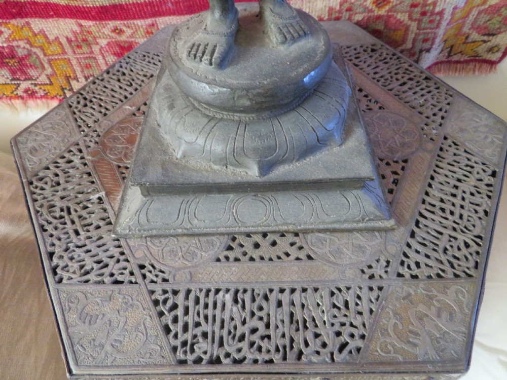 A hexagonal antique brass occasional table with pierced openwork panels, Arabic calligraphic inlays in copper and white metal, and double cabinet doors. View IX