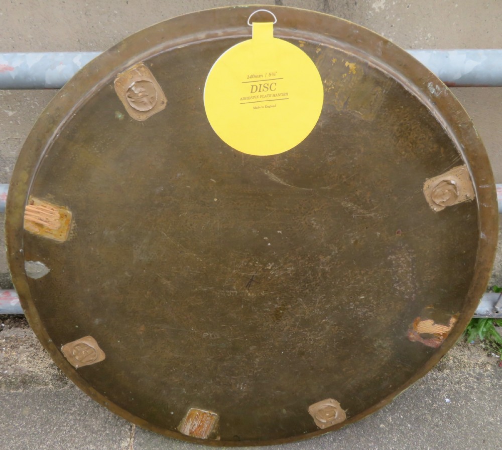 A large circular brass tray featuring detailed hand-engraved Islamic calligraphy, geometric interlace patterns, and a central star motif. View IX