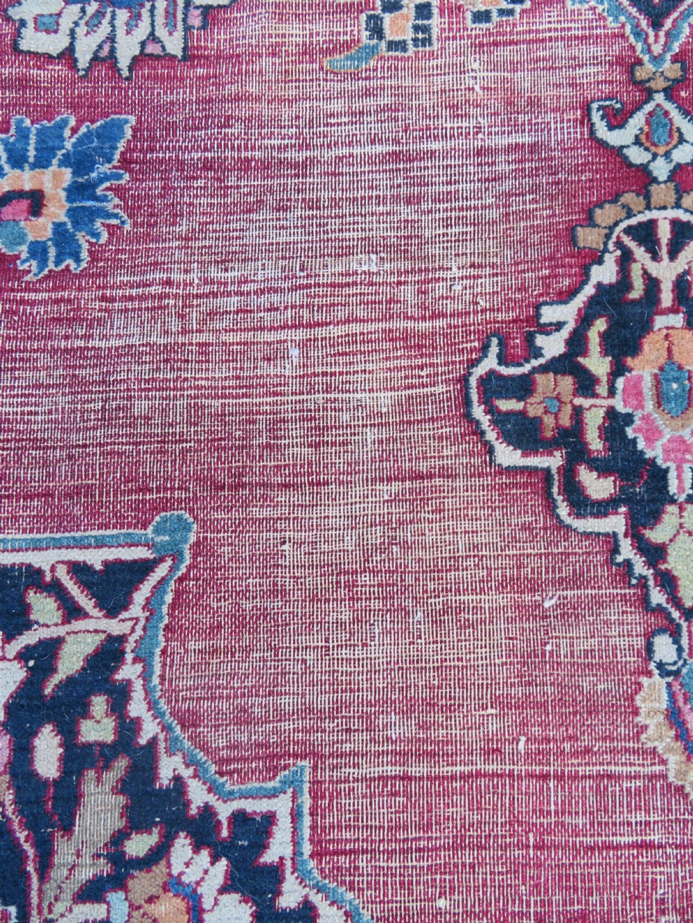 An antique hand-knotted Meshed Persian wool carpet featuring a central navy blue medallion on a distressed rose pink field surrounded by intricate floral borders. View VII
