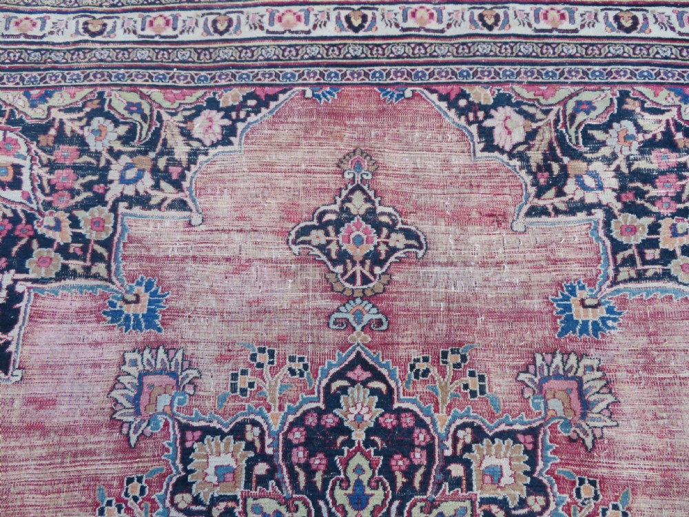 An antique hand-knotted Meshed Persian wool carpet featuring a central navy blue medallion on a distressed rose pink field surrounded by intricate floral borders. View XIX