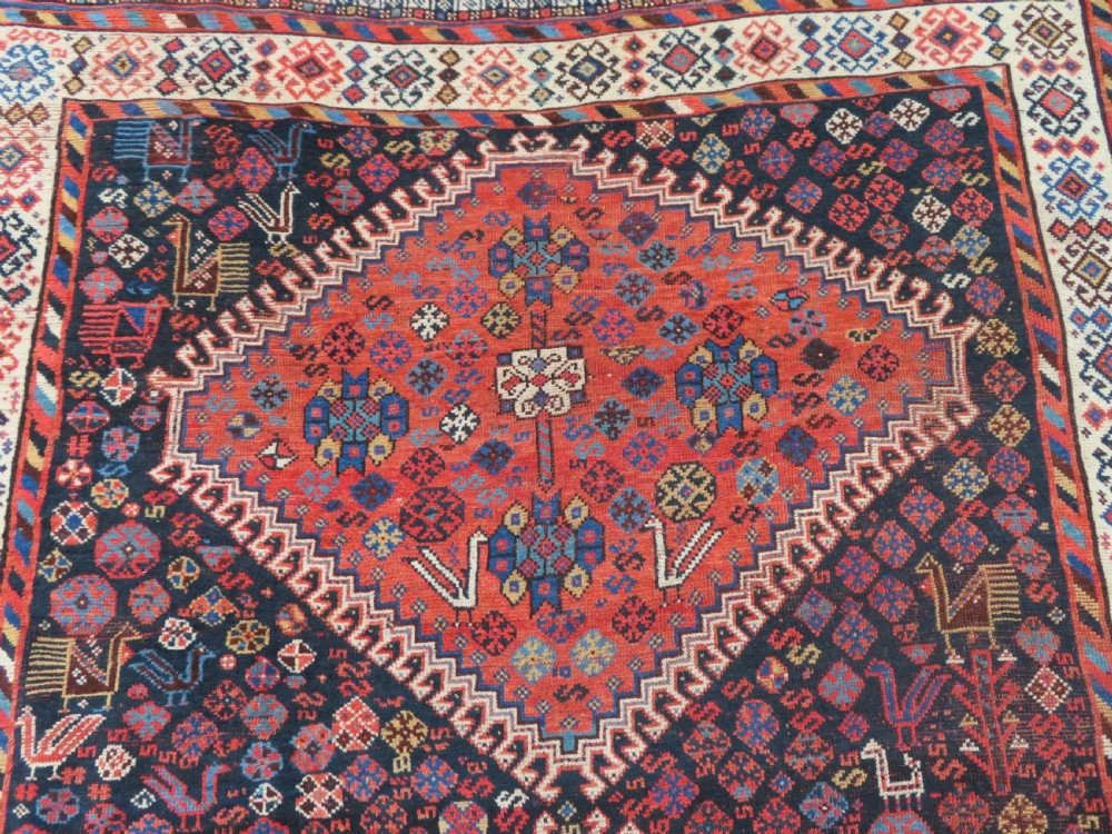 An antique Persian Luri hand-knotted wool carpet featuring three central diamond medallions surrounded by geometric tribal motifs and multi-banded borders. View V